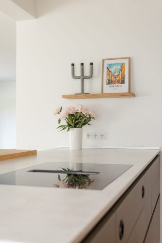 Hier sieht man das flächenbündig eingebaute Kochfeld mit integriertem Abzug. Das Bord greift das Marerial der Barplatte auf