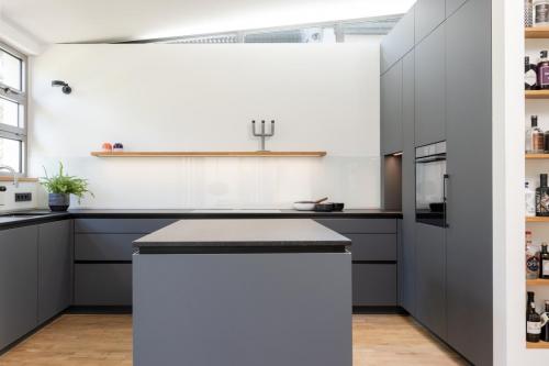 Diese dunkle grifflose Küche mit Fenix basaltgrau hat eine schöne, klare Linienführung und ist damit ganz minimalistisch.